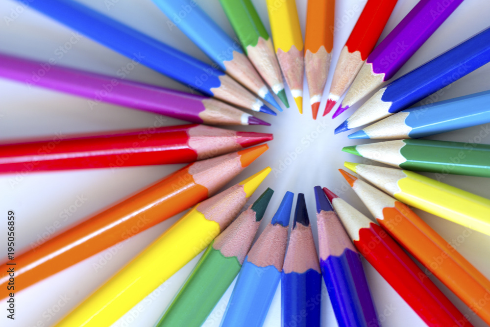    colored pencils laid out in a circle by the colors of the rainbow on a light background