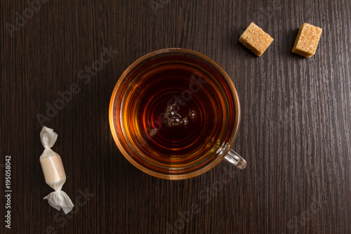 Cup of strong tea with cane sugar and candy