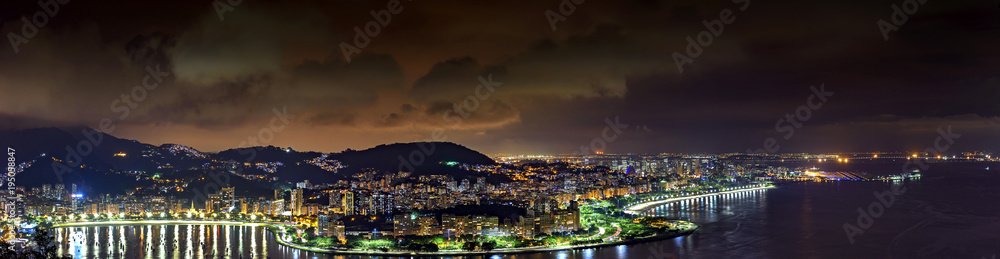 Panoramic image of Rio de Janeiro seen from above at night with its lights, hills, streets, Gaunabara bay and Santos Dumont airport