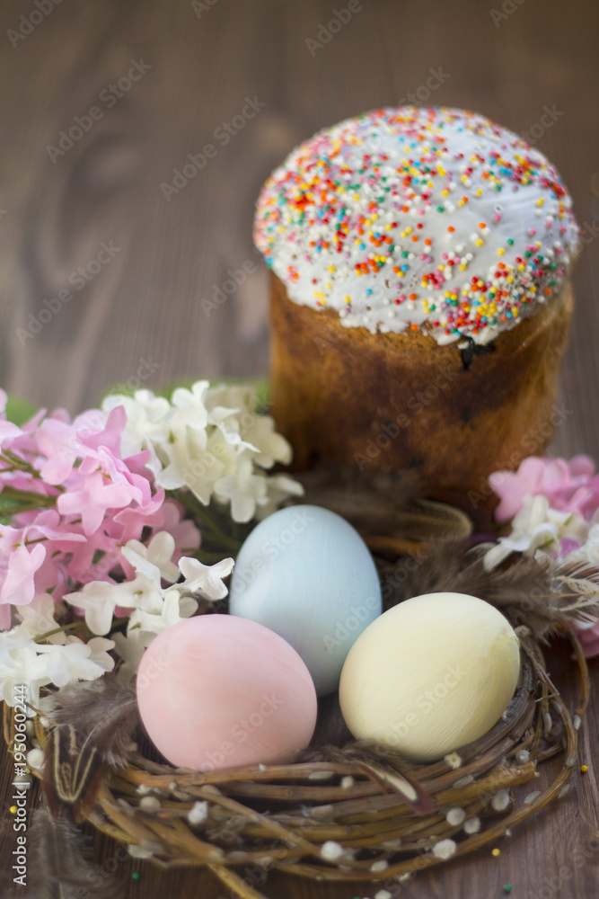 three raw colored eggs blue pink yellow in the nest on wooden background flowers cake Easter spring Christian holiday Holy three raw colored eggs blue pink yellow in the nest on wooden background flowers cake Easter spring Christian holiday Holy
