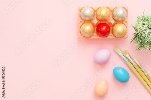 Flat lay top view colorful easter egg painted in pastel colors composition with paint brush on pink pastel color background. Easter day background top view with copy space.