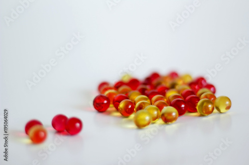 Yellow and red capsules with vitamin a and E on light background