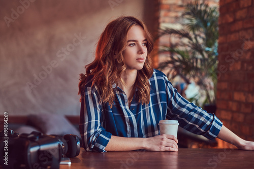 A young charming sensual girl photographer drinks a morning coff