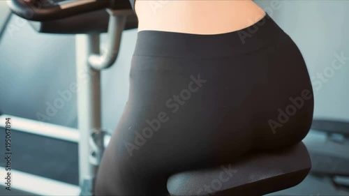 Female legs and ass riding at stationary bike in the gym photo