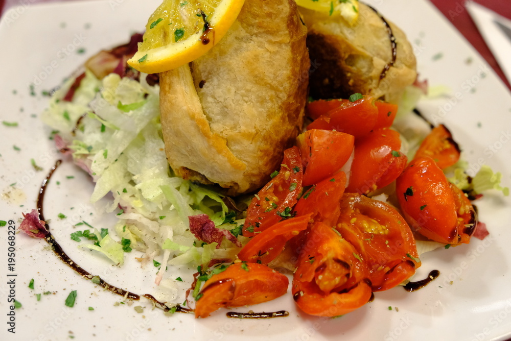 A dish of sicilian rolls, tomatoes and orange A dish of sicilian rolls, tomatoes and orange