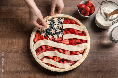 Woman preparing American flag pie on wooden background