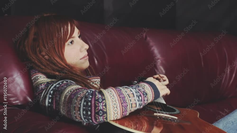 young redhead woman with drealocks play indoor on acoustic guitar young redhead woman with drealocks play indoor on acoustic guitar