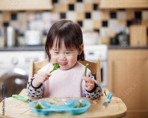 Baby girl eating messy at home kitchen