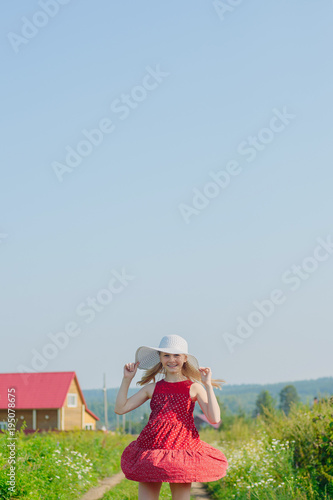 Wallpaper Mural little caucasian blonde girl in red dress and white hat with large brim posing on dirt road in countryside background Torontodigital.ca