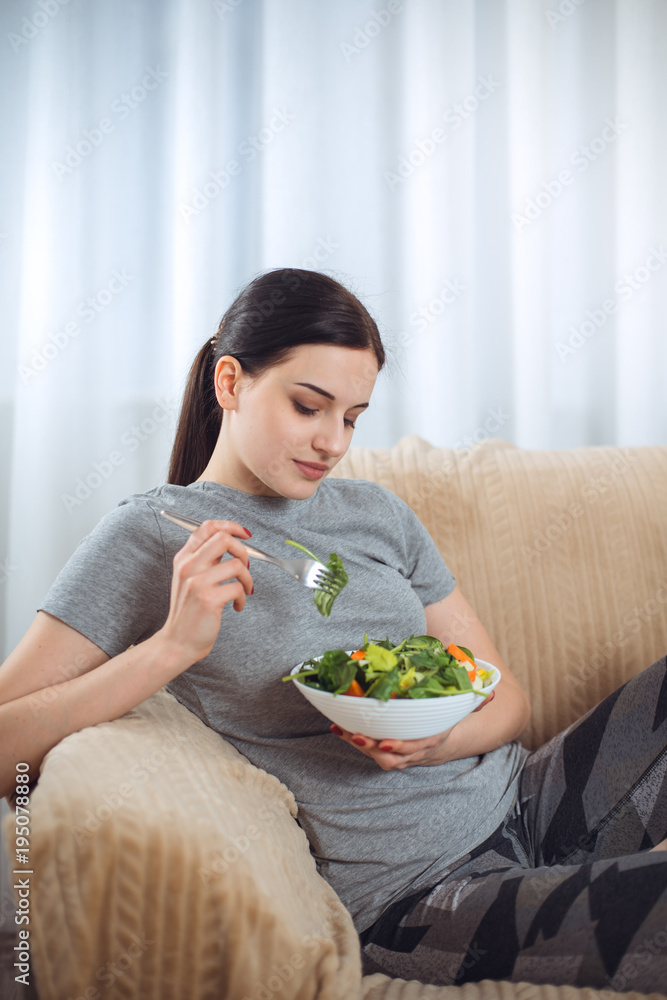 Woman in sportswear with plate of vegetarian vegetable salad. Young sporty model at livingroom. Health, beauty and fitness concept. Woman in sportswear with plate of vegetarian vegetable salad. Young sporty model at livingroom. Health, beauty and fitness concept.