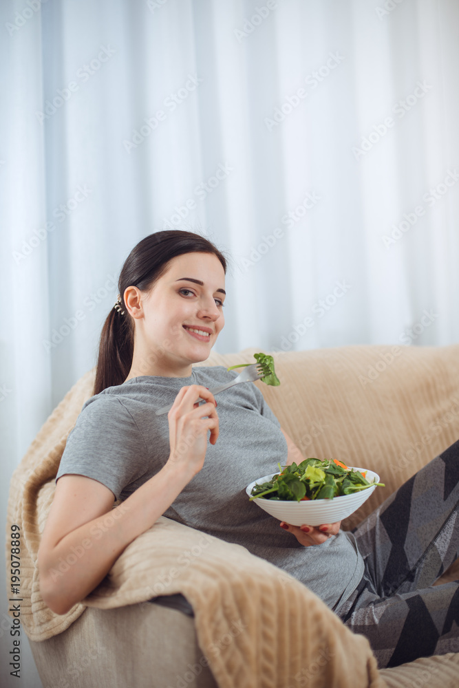 Woman in sportswear with plate of vegetarian vegetable salad. Young sporty model at livingroom. Health, beauty and fitness concept. Woman in sportswear with plate of vegetarian vegetable salad. Young sporty model at livingroom. Health, beauty and fitness concept.