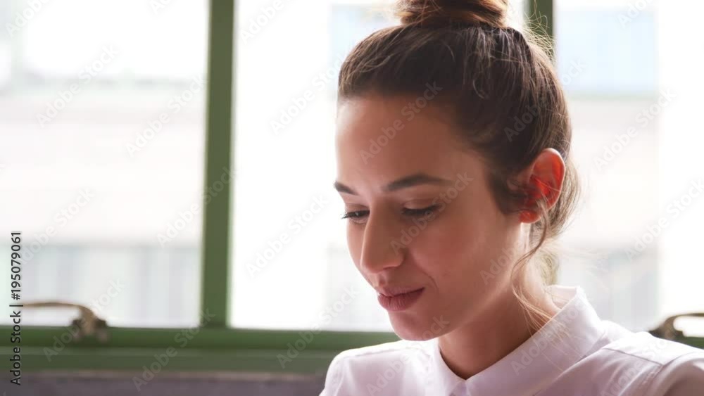 Young woman working in office, head and shoulders close up