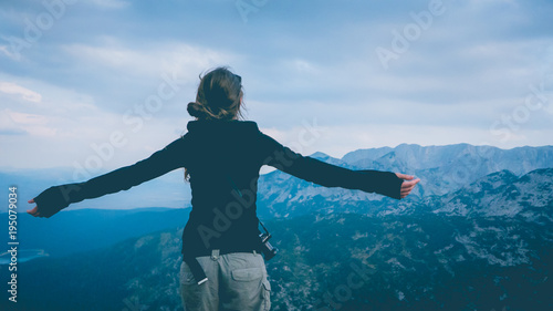 Young woman photographer feeling free at the top of the mountain
