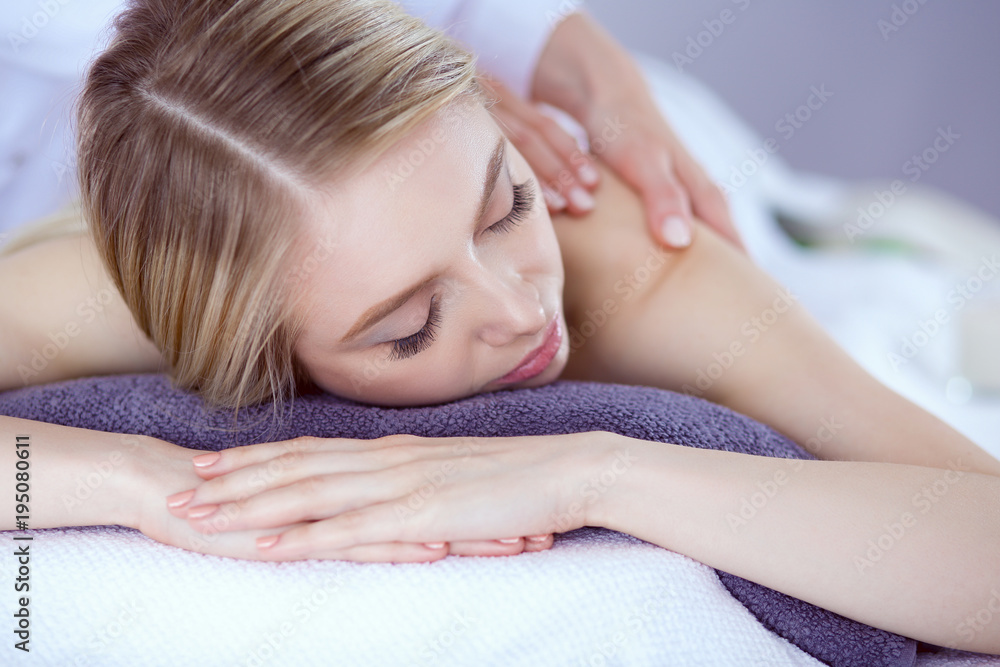Fototapeta premium Young woman lying on a massage table,relaxing with eyes closed. Woman. Spa salon
