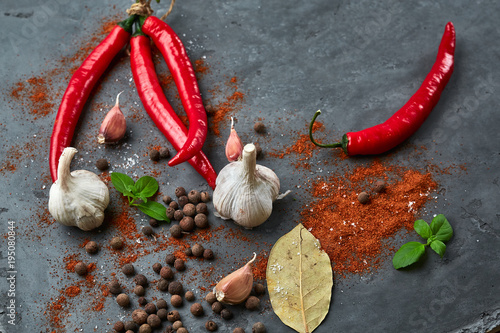 Food cooking background with chili peppers, garlic and spices on dark stone table. photo