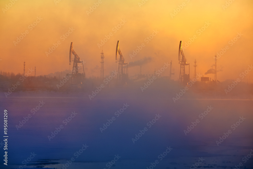 The oil sucking machines in the vapour lakeside sunrise.