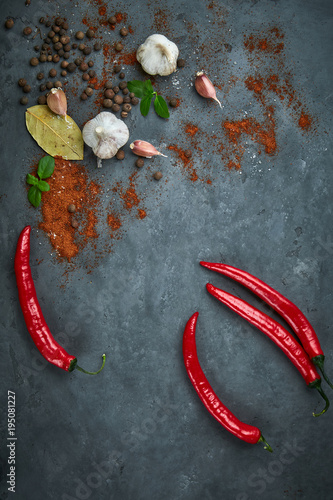 Food cooking background with chili peppers, garlic and spices on dark stone table.