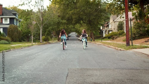 Wallpaper Mural Two teen girls riding bikes in a quiet street, front view Torontodigital.ca