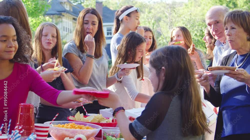Neighbours stand eating at table at a block party, close up