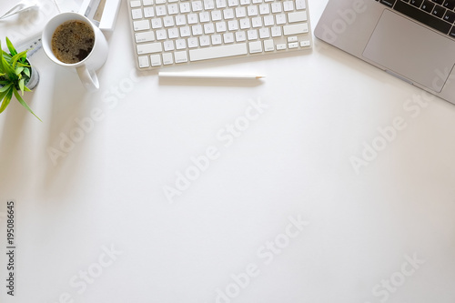 White office desk table with laptop, cup of coffee and supplies. Top view with copy space, flat lay.
