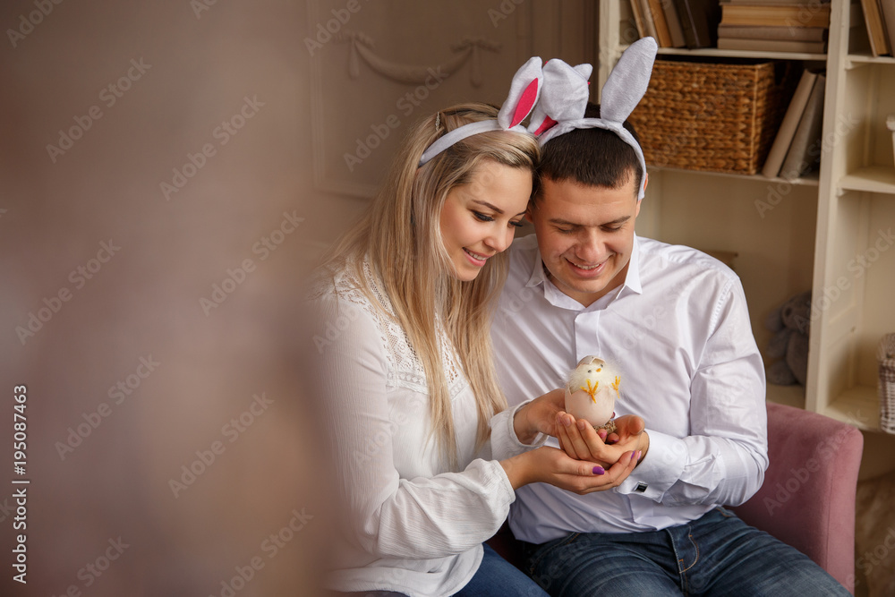 Funny couple with bunny ears holding in hands Easter egg with chick. Born new life at happy Easter day