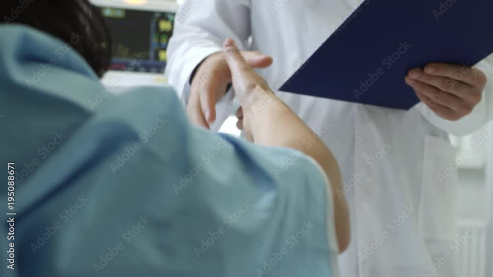 Mid-section shot of unrecognizable doctor in lab coat holding clipboard and shaking hands with patient lying in bed Mid-section shot of unrecognizable doctor in lab coat holding clipboard and shaking hands with patient lying in bed
