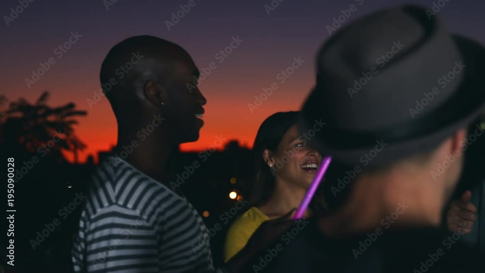 Friends dancing with glowsticks at a party on a rooftop Friends dancing with glowsticks at a party on a rooftop