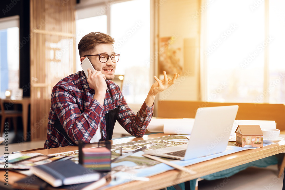 Freelancer man talking on the phone at laptop sitting at desk. Freelancer man talking on the phone at laptop sitting at desk.