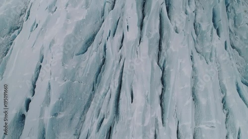 Aerial shot flying over a glacier that pans up to reveal the snowy landscape in the distance.  Pristine snow covered winter land, shot in Iceland.