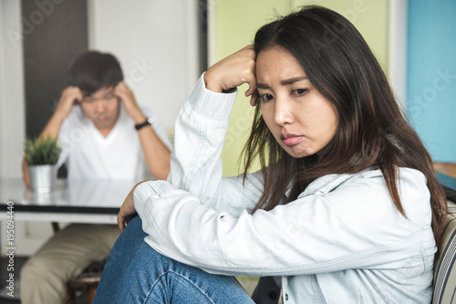 Unhappy couple not talking after an argument at home. depressed woman sitting on the sofa and sad man sitting on the table looking at girlfriend. selective focus on woman face.