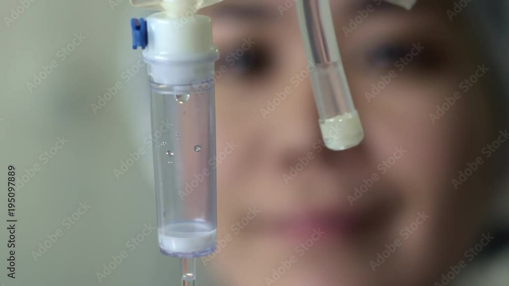 Close up of female nurse checking IV tubing while preparing infusion for patient Close up of female nurse checking IV tubing while preparing infusion for patient