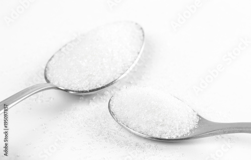 Sugar in a two spoons. Close up. Isolated on a white background