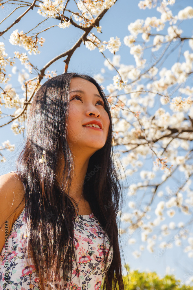 Naklejka premium Asian girl with blooming tree and white flowers