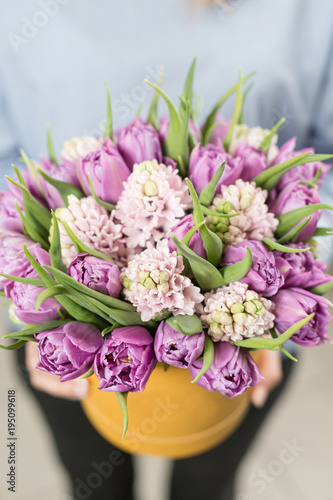 Sunny spring morning. Young happy woman holding a beautiful bunch of pink hyacinths and violet tulips in her hands. Present for a smiles girl. Flowers bouquet in headbox