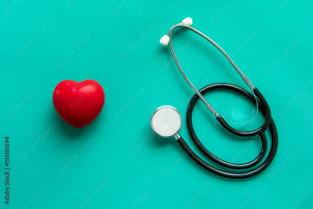 Red heart shape ball with stethoscope on green background Red heart shape ball with stethoscope on green background