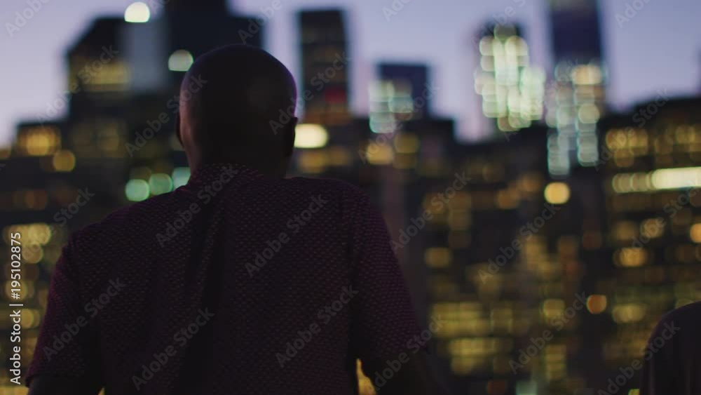 Rear View Of Friends Looking At Manhattan Skyline At Sunset