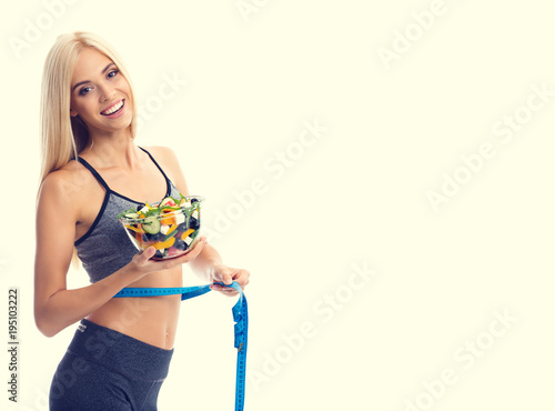 Woman in sportswear with tape measure and salad