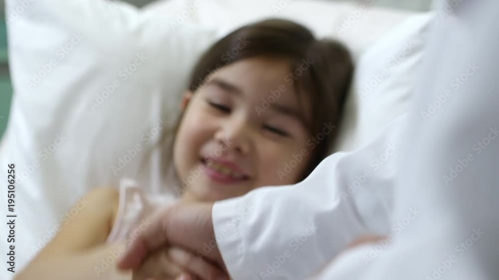 PAN of cute little girl lying in hospital bed and smiling, then shaking hands with unrecognizable doctor PAN of cute little girl lying in hospital bed and smiling, then shaking hands with unrecognizable doctor