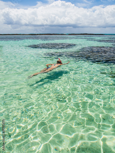 attractive woman snorkeling in crystal clear water on sunny day