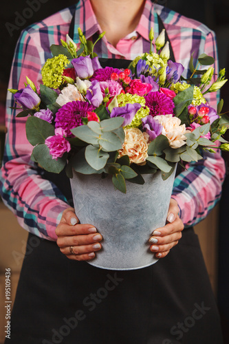 female hands holding a floral bouquet in a bucket
