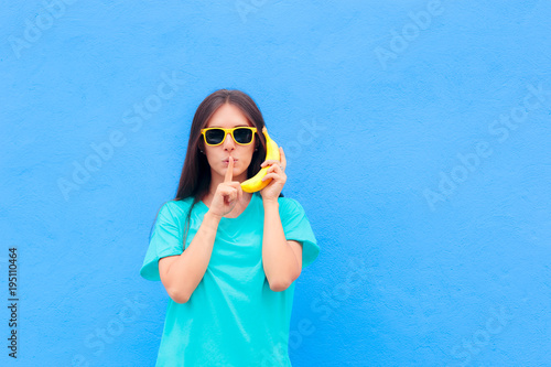 Funny Girl with Sunglasses and Banana Phone on Blue Background