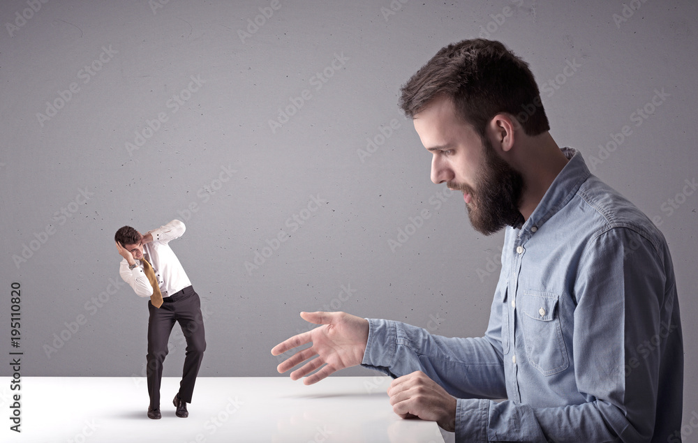 Young businessman fighting with miniature businessman Young businessman fighting with miniature businessman