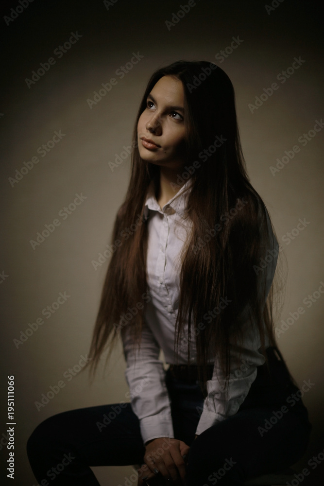 Portrait of a young adult woman in a white shirt thoughtful