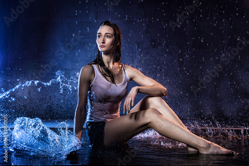 Girl with long hair during photoshoot with water in photo studio