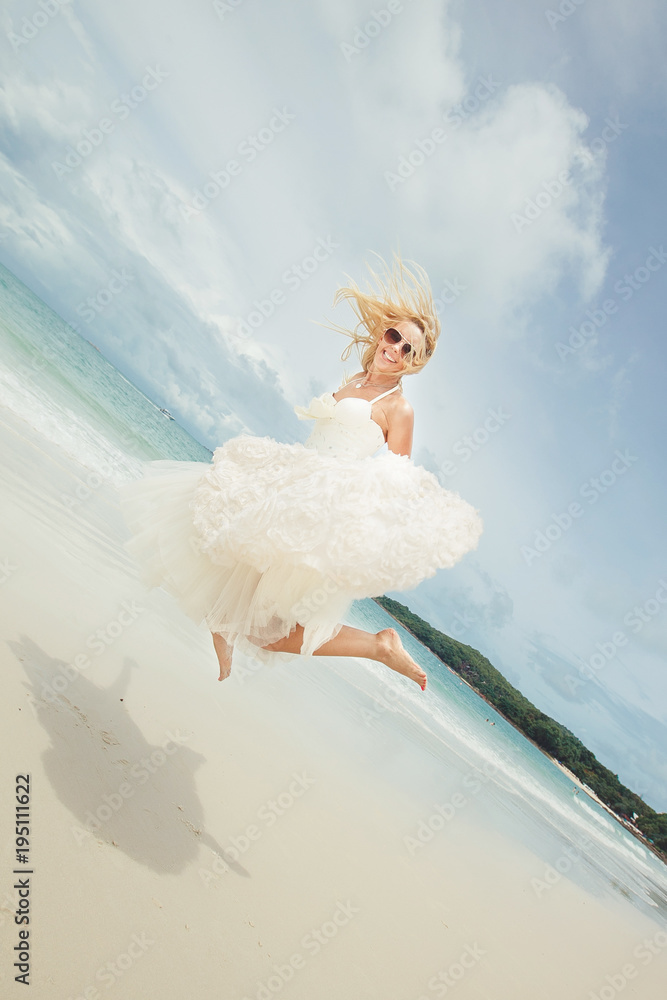 Naklejka premium happy bride jumping in wedding dress at the sea. young happy woman on beach.