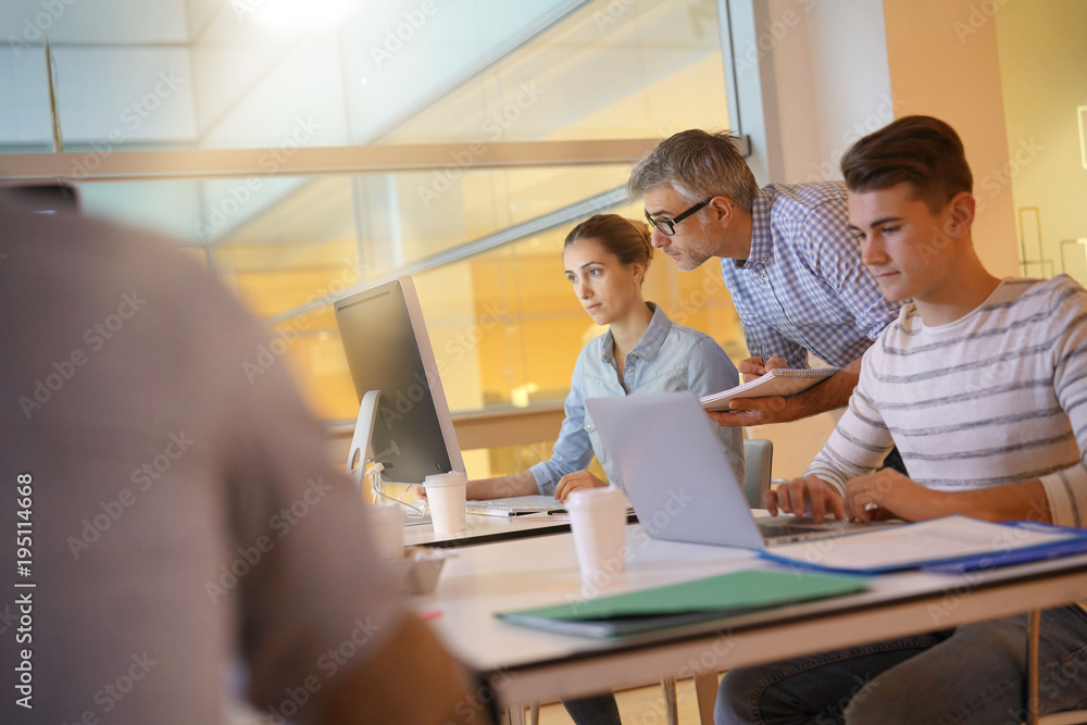Fototapeta premium Nauczyciel z uczniami na stażu w klasie informatyki