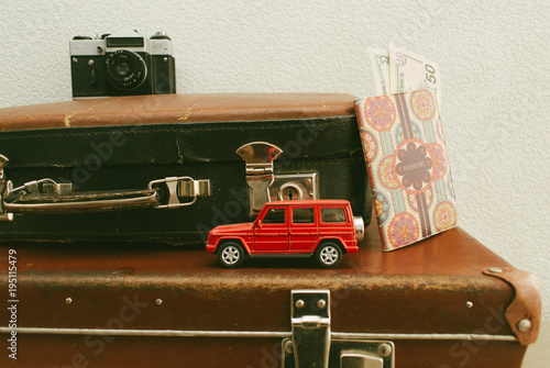 Part of vintage leather travel valises or old suitcase with passport, money, camera and toy car. Close up