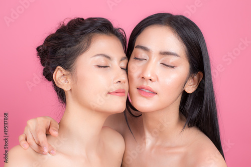 Portrait of Two Beautiful Asian Woman. Beautiful Woman looking to camera. People with Youth and Skin Care Concept. isolated on pink background.