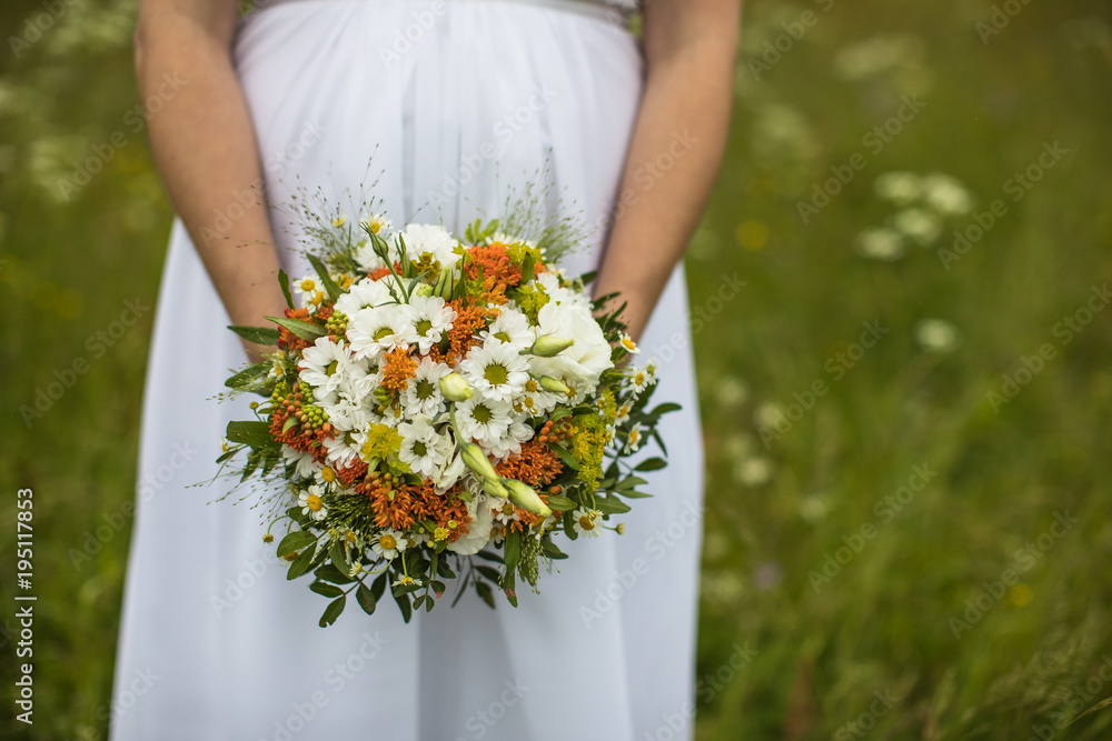 Beautiful bride with bouquet. Fashion brunette model outdoors. Portrait beauty model in white bridal dress holding flowers