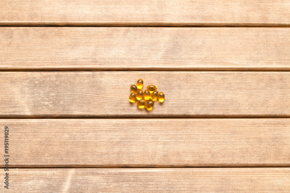 Fototapeta premium A few pills scattered on a wooden table . On a brown background